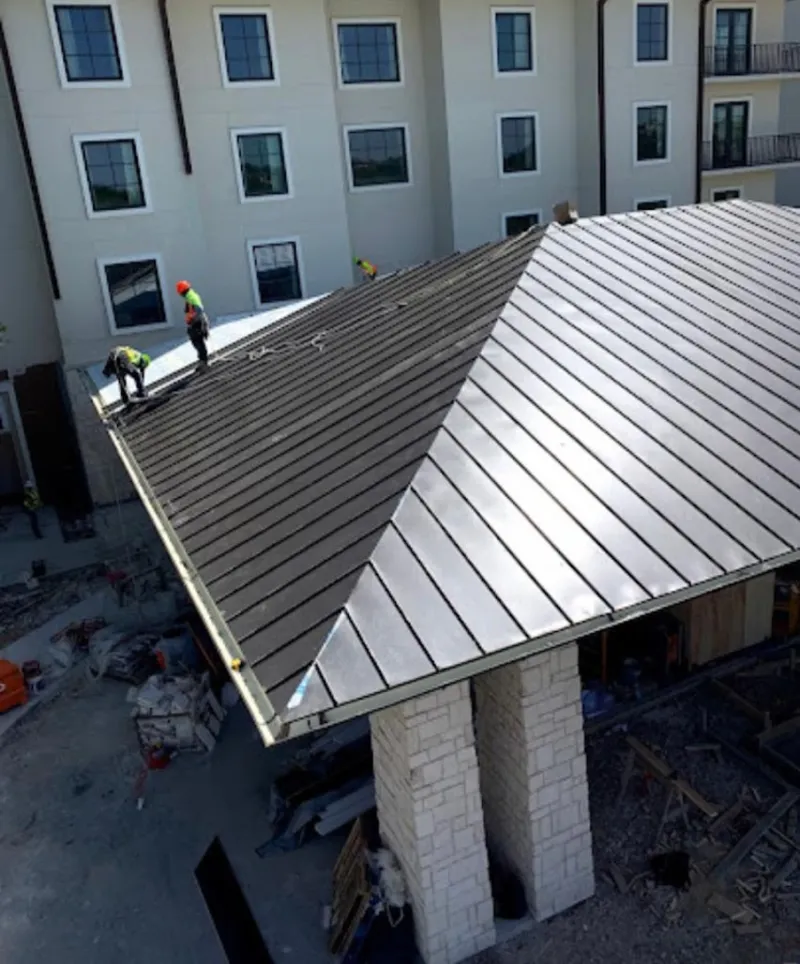 Crew installing standing seam metal roof panels on a commercial project in Florence
